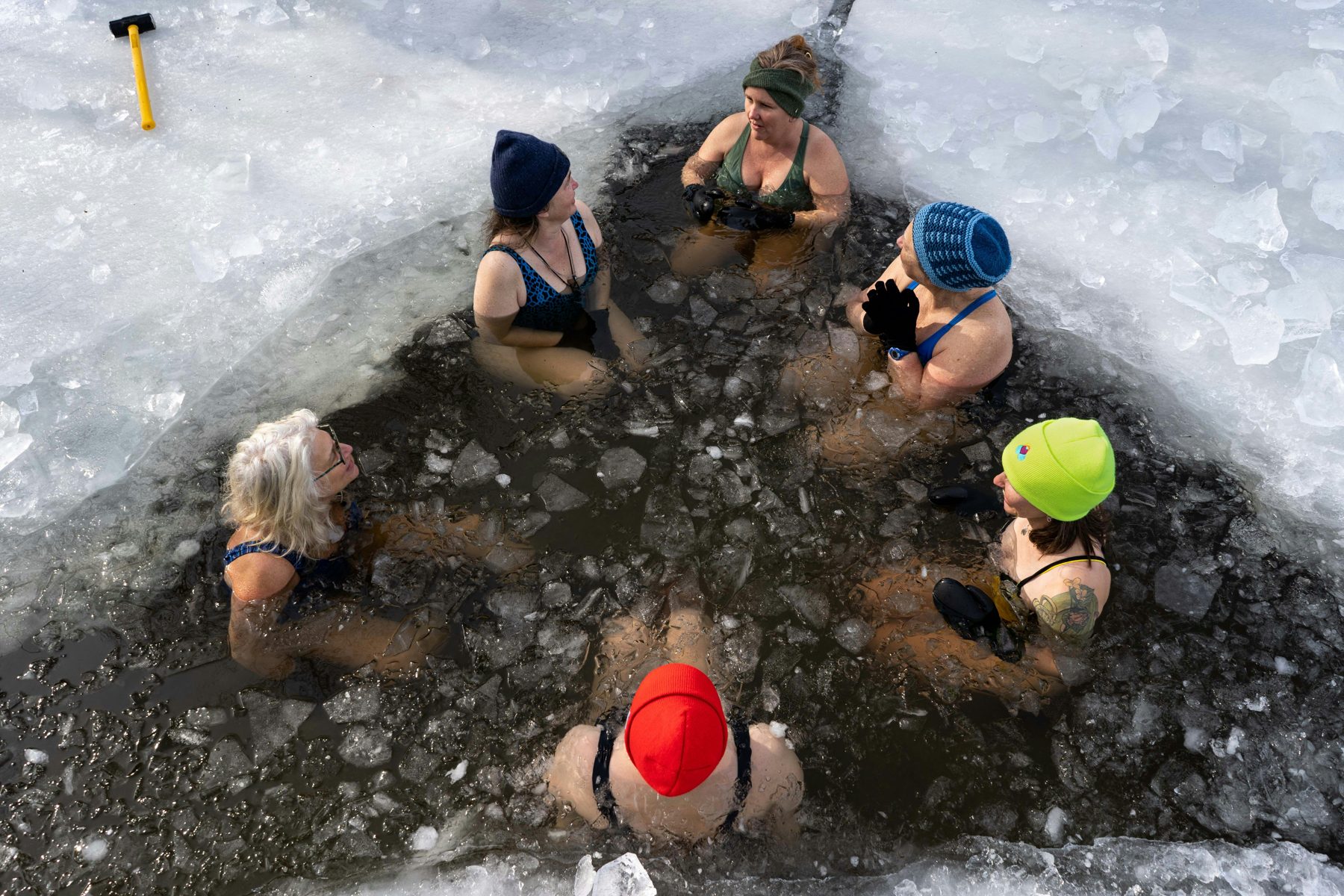 Friends cold plunging in an ice hole